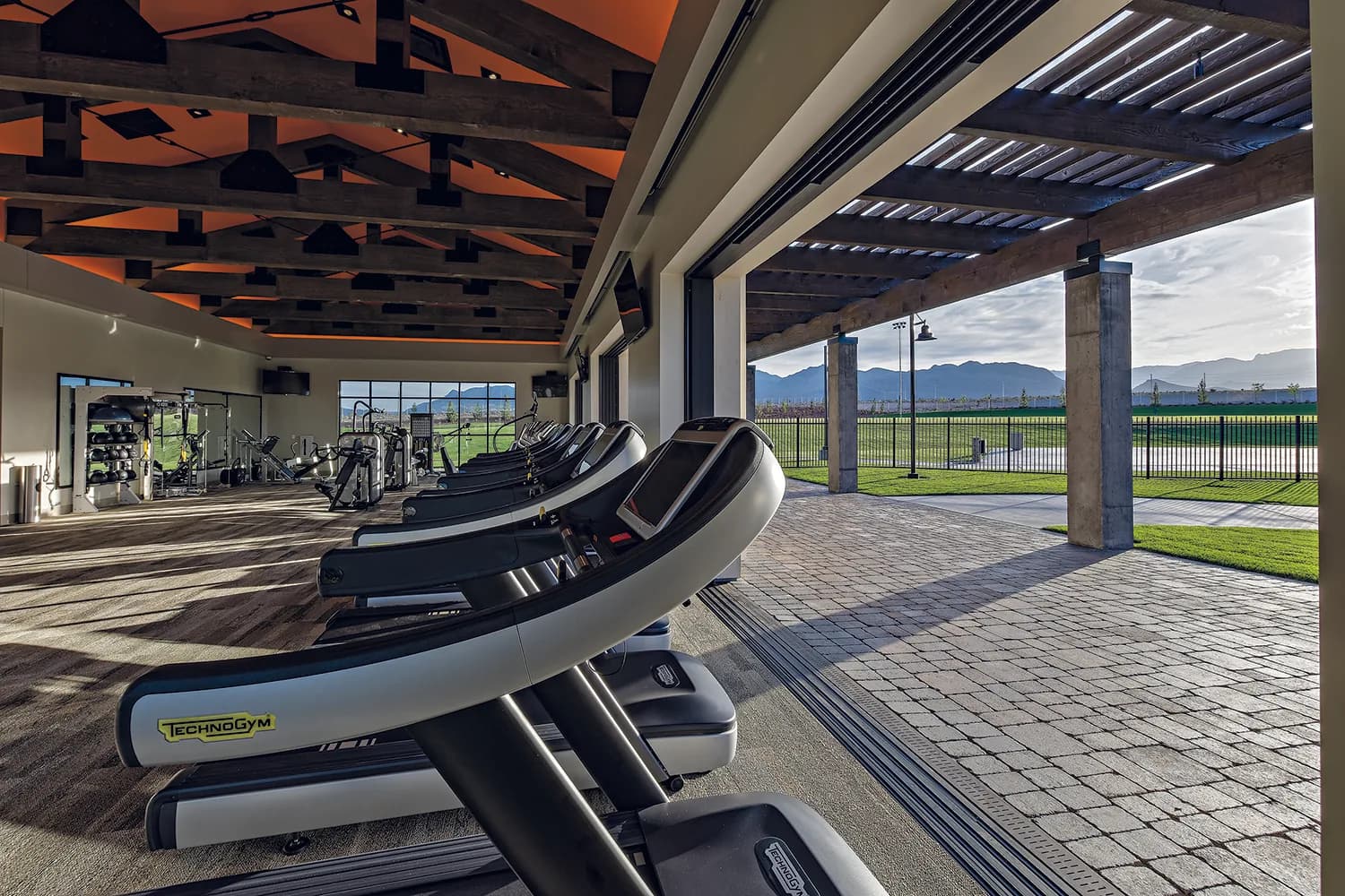 Indoor fitness center at the Skye Canyon community center, with rows of cardio equipment facing an open-air patio.