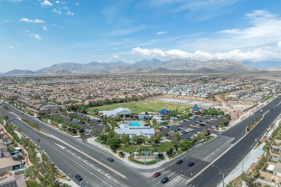 Aerial view of a community park and clubhouse within the Kyle Canyon growth area, with sports courts, a pool and surrounding new-construction homes.